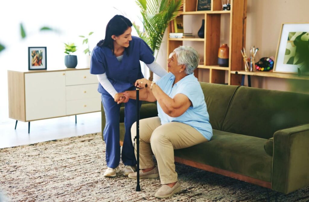 A medical caregiver helps a senior adult with a walking stick in the lounge of a personal care community in Kentucky.