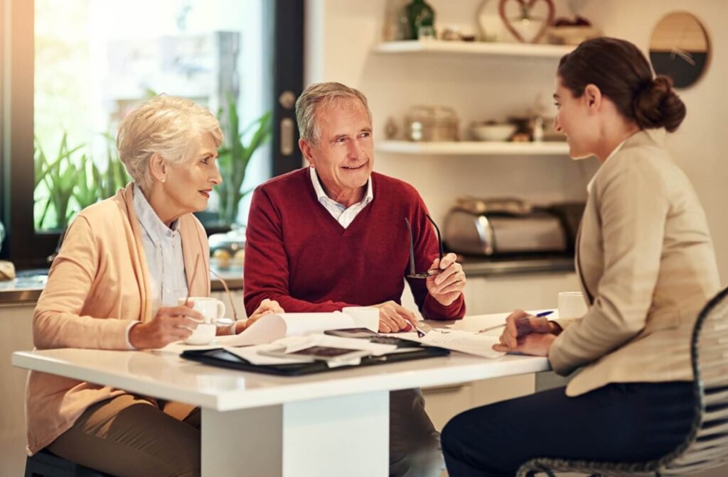 An older couple sits across from a senior living representative in a well-decorated office while sorting through paperwork