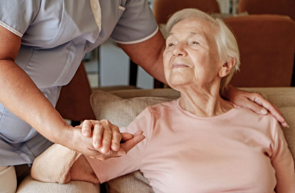 An appreciative caregiver gently lives one arm to accept help from a caregiver in personal care