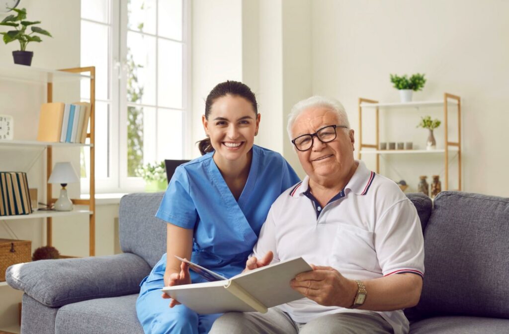 A nurse and a senior resident smile while looking through a photo album together.